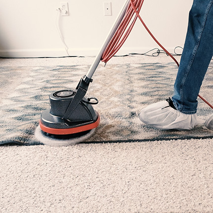 Kevin running the vacuum scrubber over the rug.